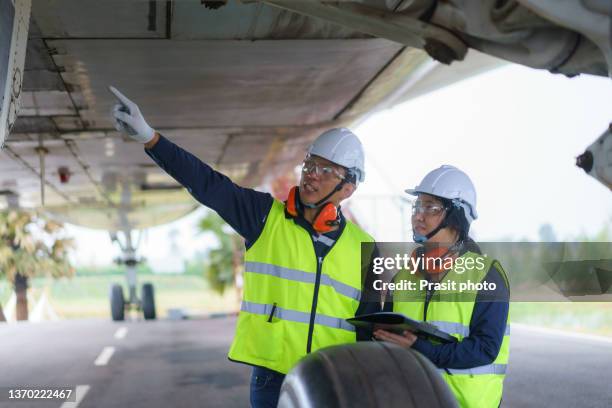 asian man and woman engineer maintenance airplane team repairs, fixes, modernization and renovation in front airplane from  in airport."n - aviation worker stock pictures, royalty-free photos & images