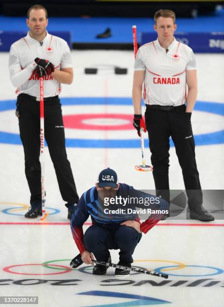 Geoff Walker and Marc Kennedy of Team Canada looks on as John Shuster of Team United States sights his line during the Men's Curling Round Robin...