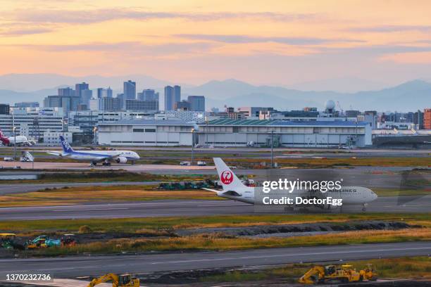 japan airlines and all nippon airways taxiing on the runway of tokyo haneda international airport with tokyo skyscrapers background - tokyo international airport bildbanksfoton och bilder