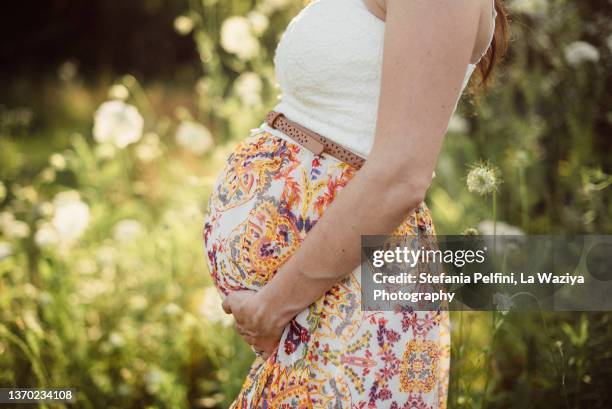side view of woman's pregnant belly in nature. - umstandskleidung stock-fotos und bilder