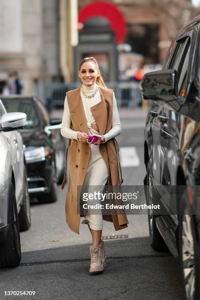Olivia Palermo wears gold earrings, a gold large chain necklace, a white latte turtleneck long sleeves / cut-out chest / midi dress, a brown...