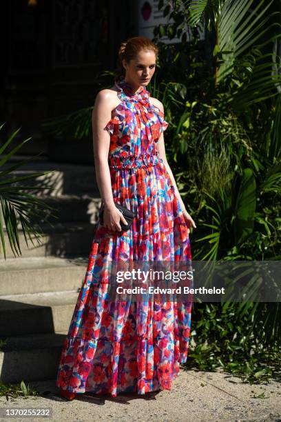 Alexina Graham wears a beige / red / purple / blue flower print pattern ruffled halter-neck / sleeveless / belted / long pleated dress, a black shiny...