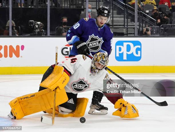 Juuse Saros of the Nashville Predators passes the puck against Sebastian Aho of the Carolina Hurricanes during the game between the Metropolitan...