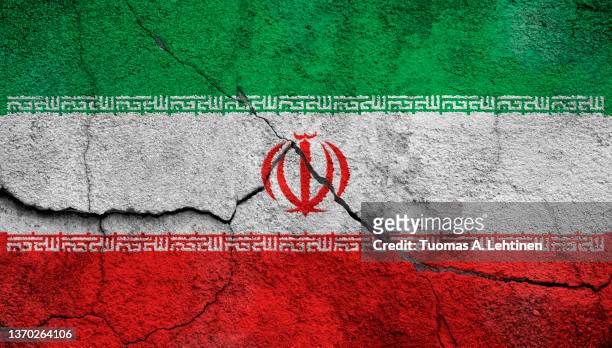 full frame photo of a weathered flag of iran painted on a cracked wall. - iranian flag stock pictures, royalty-free photos & images
