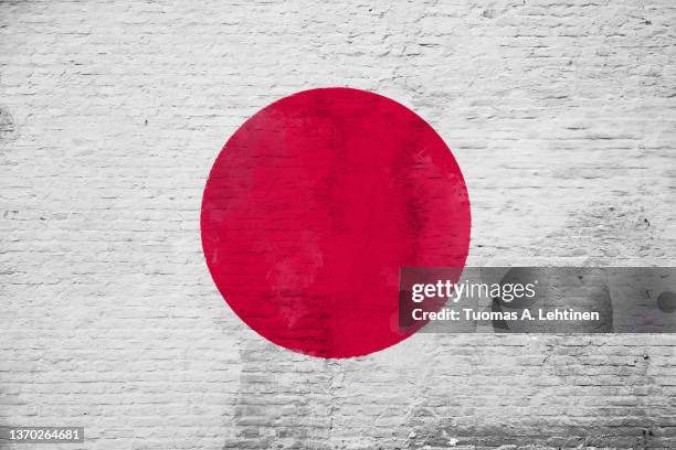 full frame photo of a weathered flag of japan painted on a plastered brick wall. - japanische flagge stock-fotos und bilder