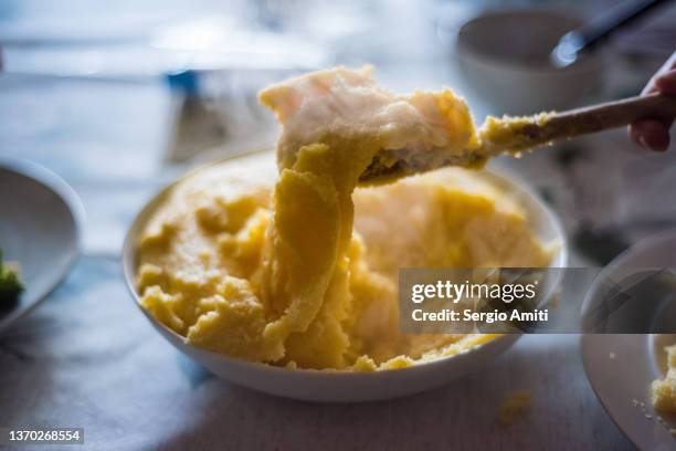 serving polenta from a serving plate using a wooden spoon - polenta fotografías e imágenes de stock