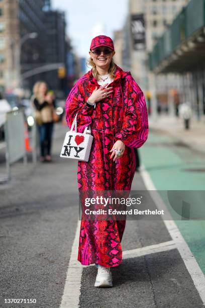 Guest wears a red / pink / black snake print pattern cap from Ivy Park, a matching red / pink / black snake print pattern oversized long coat from...