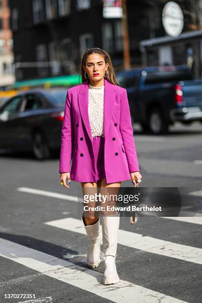 Guest wears silver large earrings, a white latte fluffy high neck pullover, a neon purple blazer jacket, a matching neon purple suit skirt, white /...