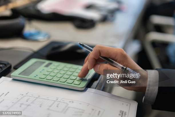 man working hard at office workstation using calculator to calculate - accounting stock pictures, royalty-free photos & images