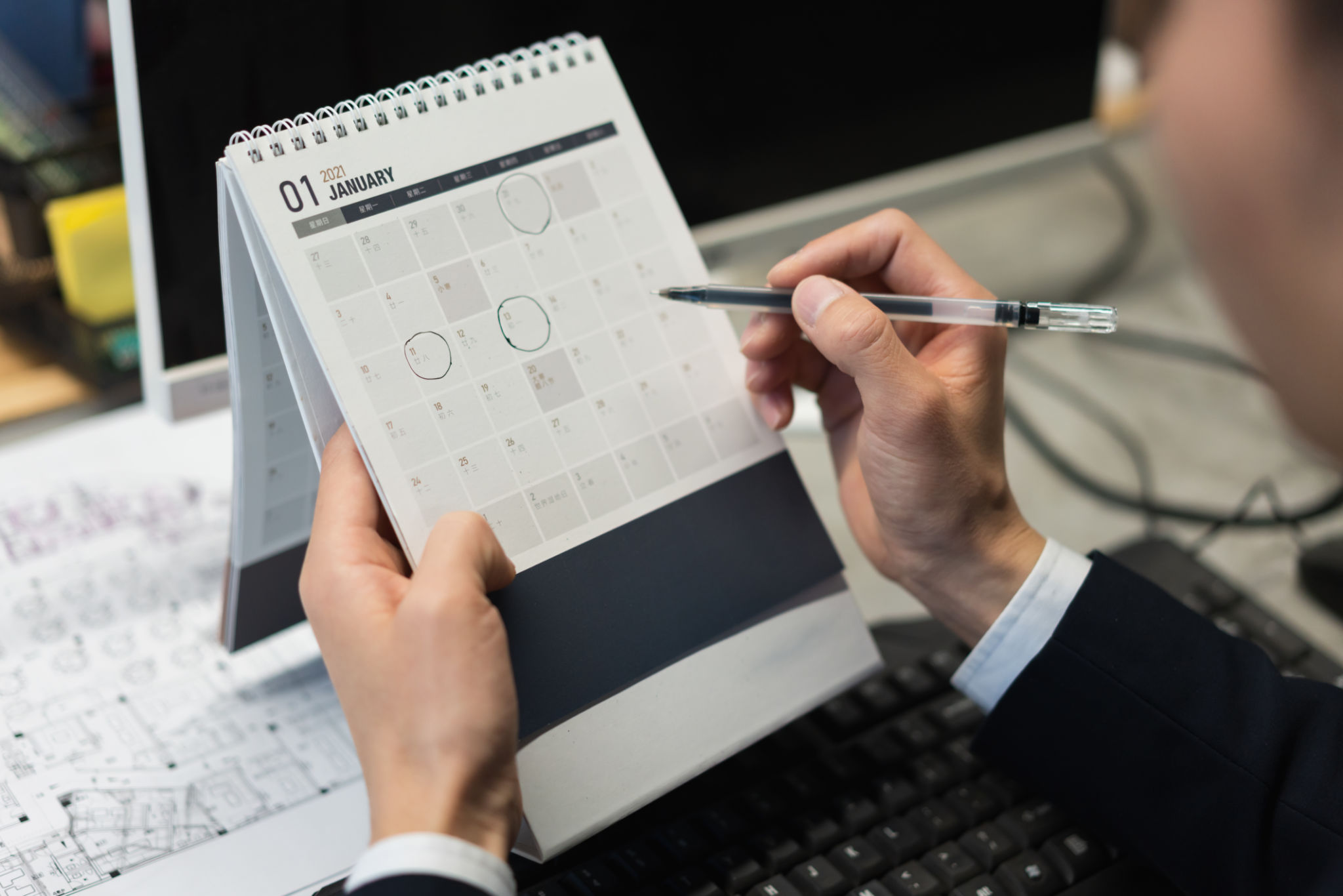 Asian male white collar marking the date on the desk calendar Asian male white collar marking the date on the desk calendar