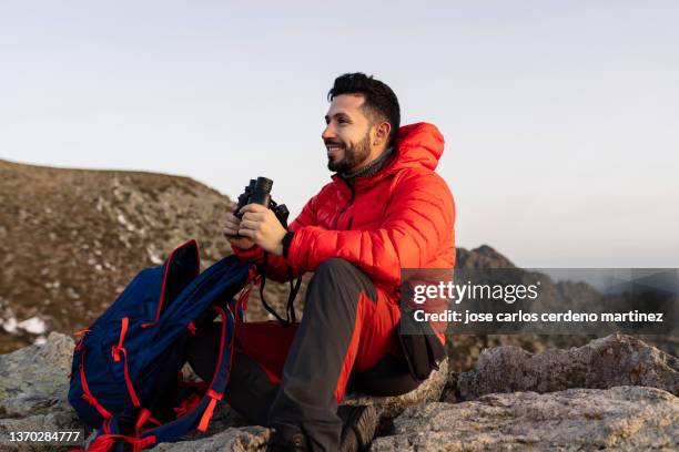 backpacker man with binoculars observes from the mountain - 望遠鏡　男性 ストックフォトと画像