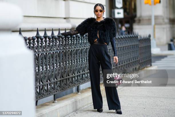 Guest wears brown sunglasses, a black oversized fur / fluffy cropped cloak, a black embroidered sequins pattern / cut-out / long sleeves body, high...