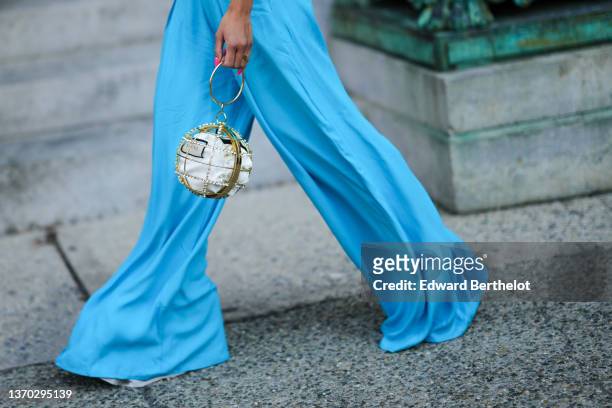 Guest wears a blue halter-neck / shoulder-off / cut-out waist long wide legs jumpsuit, gold ring, a white fabric in gold metallic ball and...