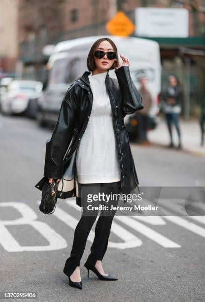 Chriselle Lim is seen wearing a black leather coat, white dress and black pants is seen outside Proenza Schouler during New York City Fashion Week on...