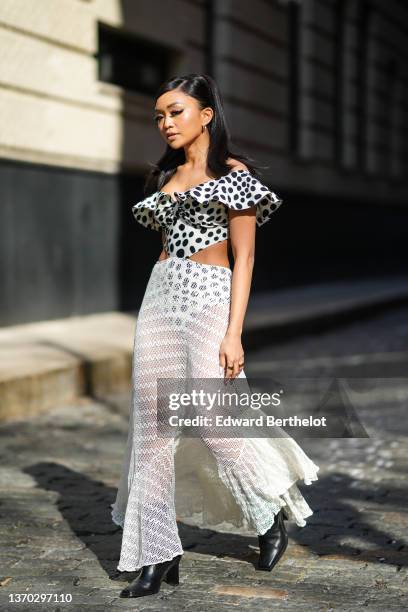 Guest wears gold earring, a white with black polka dots print pattern shoulder-off / ruffled collar / cut-out waist body, high waist white fishnet /...