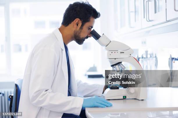 scientist in laboratory looking into microscope - stem cell research stockfoto's en -beelden