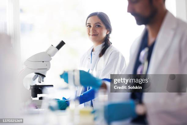 two scientist working together in laboratory, using microscopes - screening of magnolia pictures i give it a year arrivals stockfoto's en -beelden