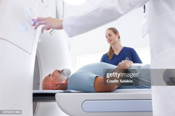 medical professionals helping mature man in ct scanner - computerized tomography stock pictures, royalty-free photos & images