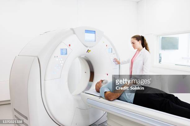 radiographer helping patient in ct scanner - medical scanning equipment stock pictures, royalty-free photos & images