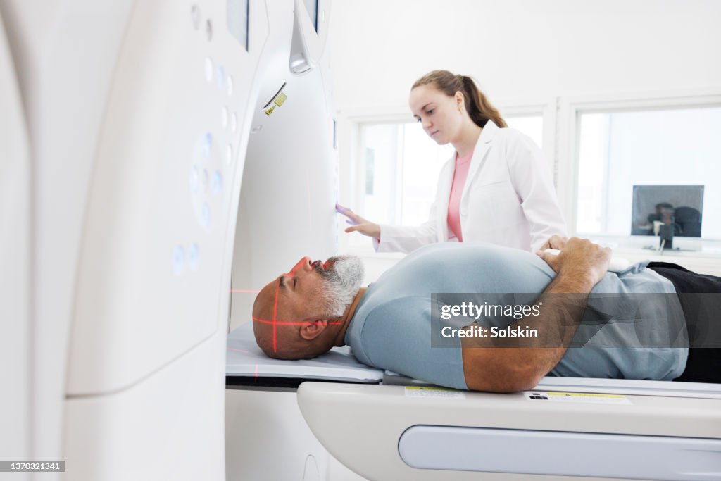 Radiographer helping patient in CT scanner