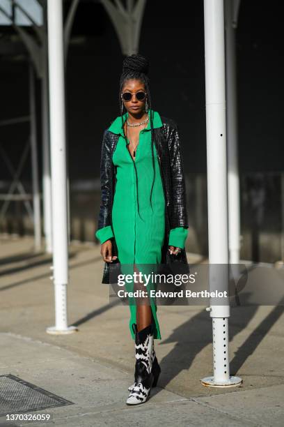 Guest wears sunglasses, silver pendant earrings, silver large chain necklaces, a green ribbed long buttoned polo dress, a black shiny leather...