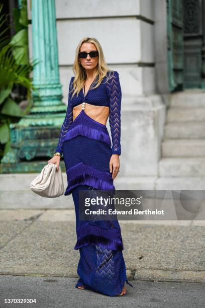 Guest wears black sunglasses, gold earrings, a navy blue embossed striped pattern V-neck / cut-out waist / long sleeves / fringed / long dress, a...