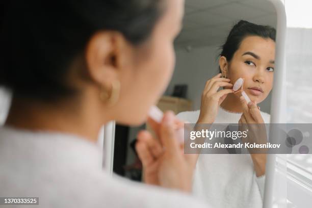 beautiful asian woman doing face massage with pink quartz roller during daily beauty morning routine - jade foto e immagini stock