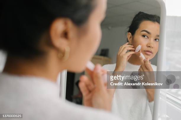 beautiful asian woman doing face massage with pink quartz roller during daily beauty morning routine - jade stock pictures, royalty-free photos & images
