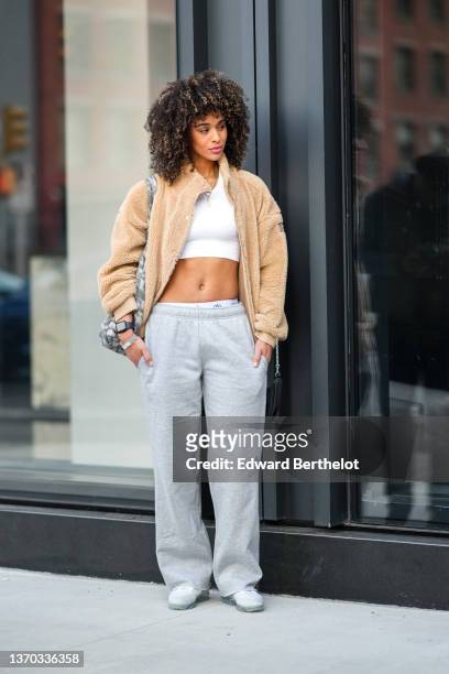 Guest wears gold earrings, gold chain necklaces, a white cropped tank-top, a beige fluffy zipper high neck coat, a white and gray tie and dye print...