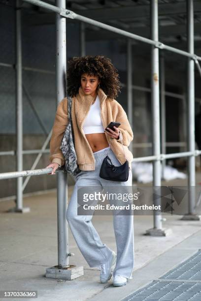 Guest wears gold earrings, gold chain necklaces, a white cropped tank-top, a beige fluffy zipper high neck coat, a white and gray tie and dye print...