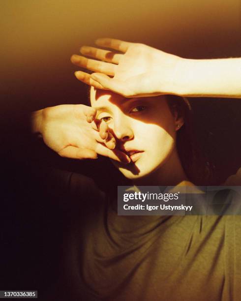 close-up of young woman in sunlight - hand covering face stock pictures, royalty-free photos & images