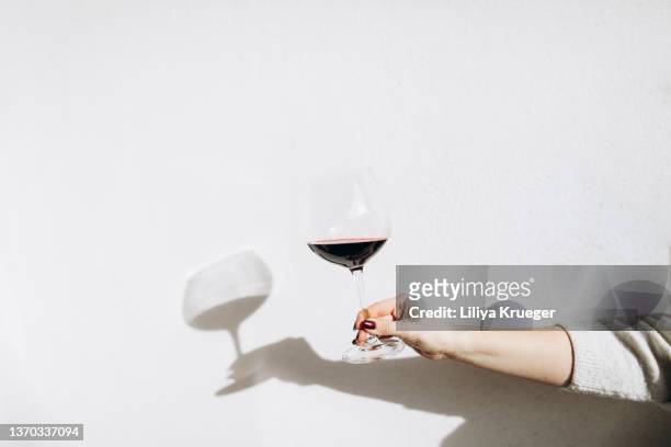 women's hand holding a glass of red wine. - red wine glass stock-fotos und bilder