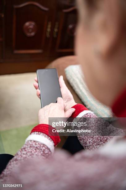 elderly woman using mobile phone at home - aburrimiento stock-fotos und bilder