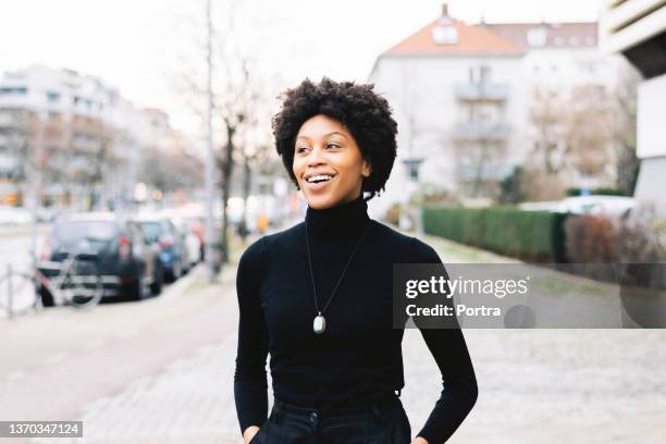 portrait of a happy young african american woman walking down the city street - polo tee stock pictures, royalty-free photos & images