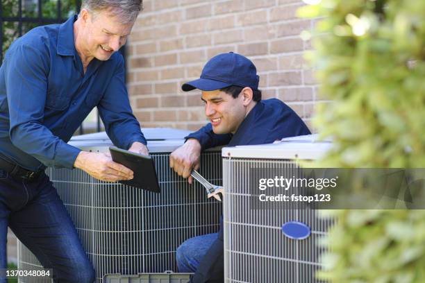 multi-ethnic team of blue collar air conditioner repairmen at work. - ventilador imagens e fotografias de stock