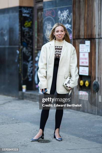 Guest wears gold earrings, a beige with brown and black print pattern wool pullover, a white leather oversized blazer jacket, a white leather...