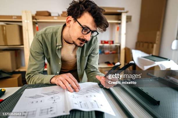 young man looking metal tools at table in workshop - instruction manual stock pictures, royalty-free photos & images