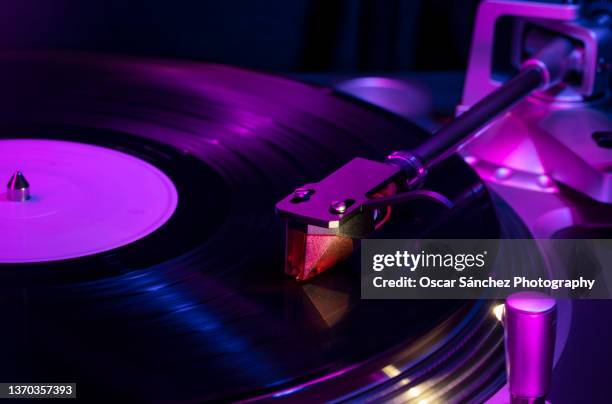 needle of a record player playing a vinyl with club lights - record player fotografías e imágenes de stock