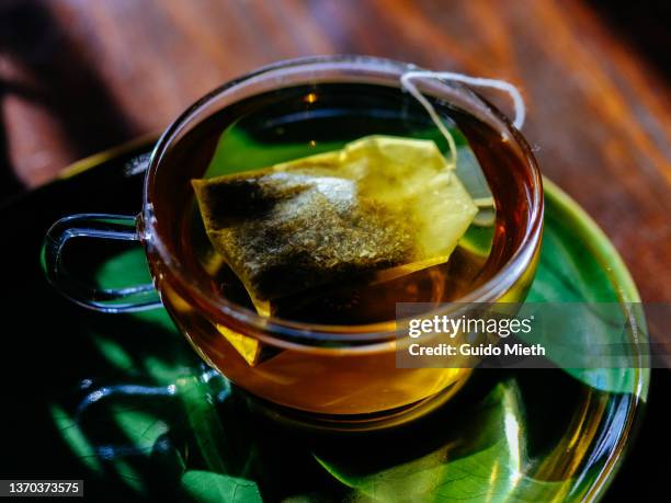 glass of tea beside on a green plate. - ティーバッグ ストックフォトと画像