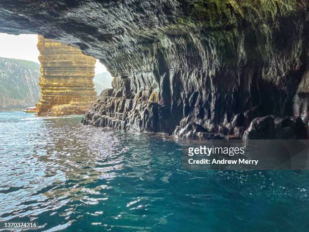 inside sea cave, rock formation outside, rippled turquoise water - ígnea fotografías e imágenes de stock