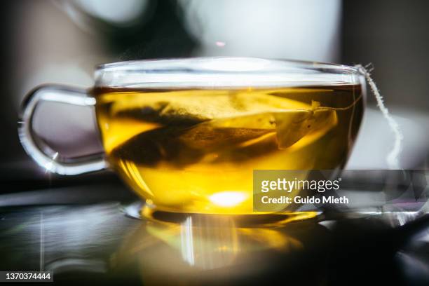 cup of hot golden looking herbal tea. - chamomile tea stock pictures, royalty-free photos & images