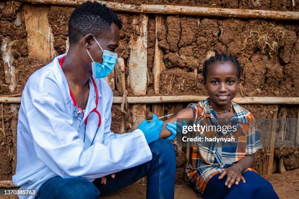 doctor is doing an injection to young african girl in small village, east africa - vaccine africa stock pictures, royalty-free photos & images