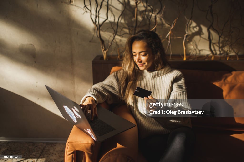 Young smiling Woman making online purchases in Cafe with Credit Card and Laptop