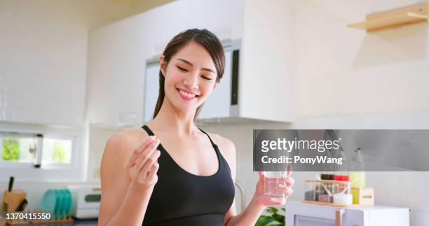 la mujer toma vitamina o medicamento - vitaminas fotografías e imágenes de stock