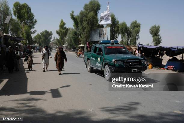 Taliban police force walk victoriously alongside a police pickup truck where an Islamic Emirate of Afghanistan flag is seen amass on the bonnet on...