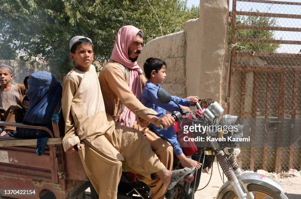 Pashtun man rides on an engined tricycle with his sons by the wheel and other family members sat in the back on September 23, 2021 in Panjwai,...
