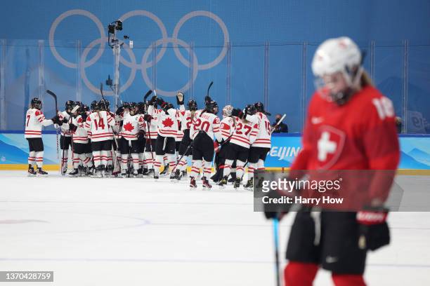 Team Canada celebrate around goaltender Ann-Renee Desbiens on the ice after their 10-3 win as Stefanie Wetli of Team Switzerland looks on during the...