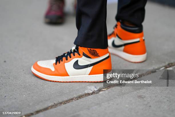 Guest wears black suit pants, a white and orange shiny leather Air Jordan ankle sneakers from Nike, outside Song Jun Wan, during New York Fashion...