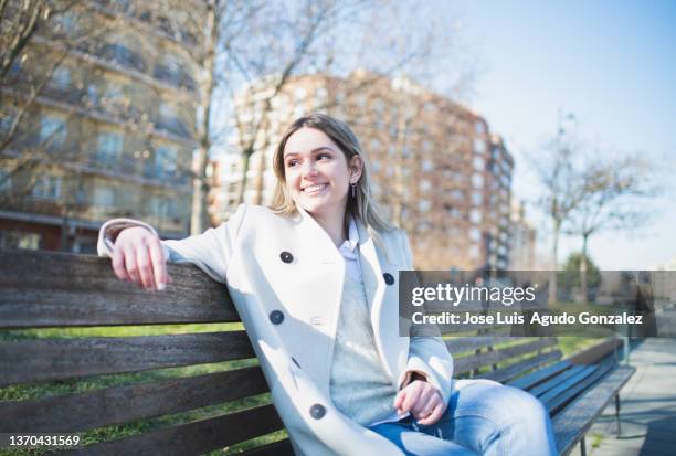 cheerful female resting on bench - fall park stock-fotos und bilder