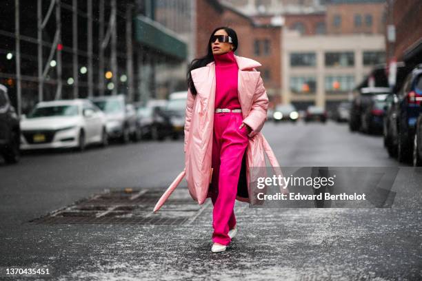 Miki Cheung wears black futurist sunglasses, a neon pink turtleneck pullover, a white leather belt from Saint Laurent Paris, matching neon pink large...